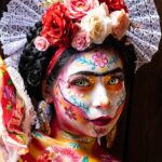 Colorful Day of the Dead makeup with floral headpiece and lace details.
