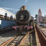 Historic steam train and station under a clear blue sky.