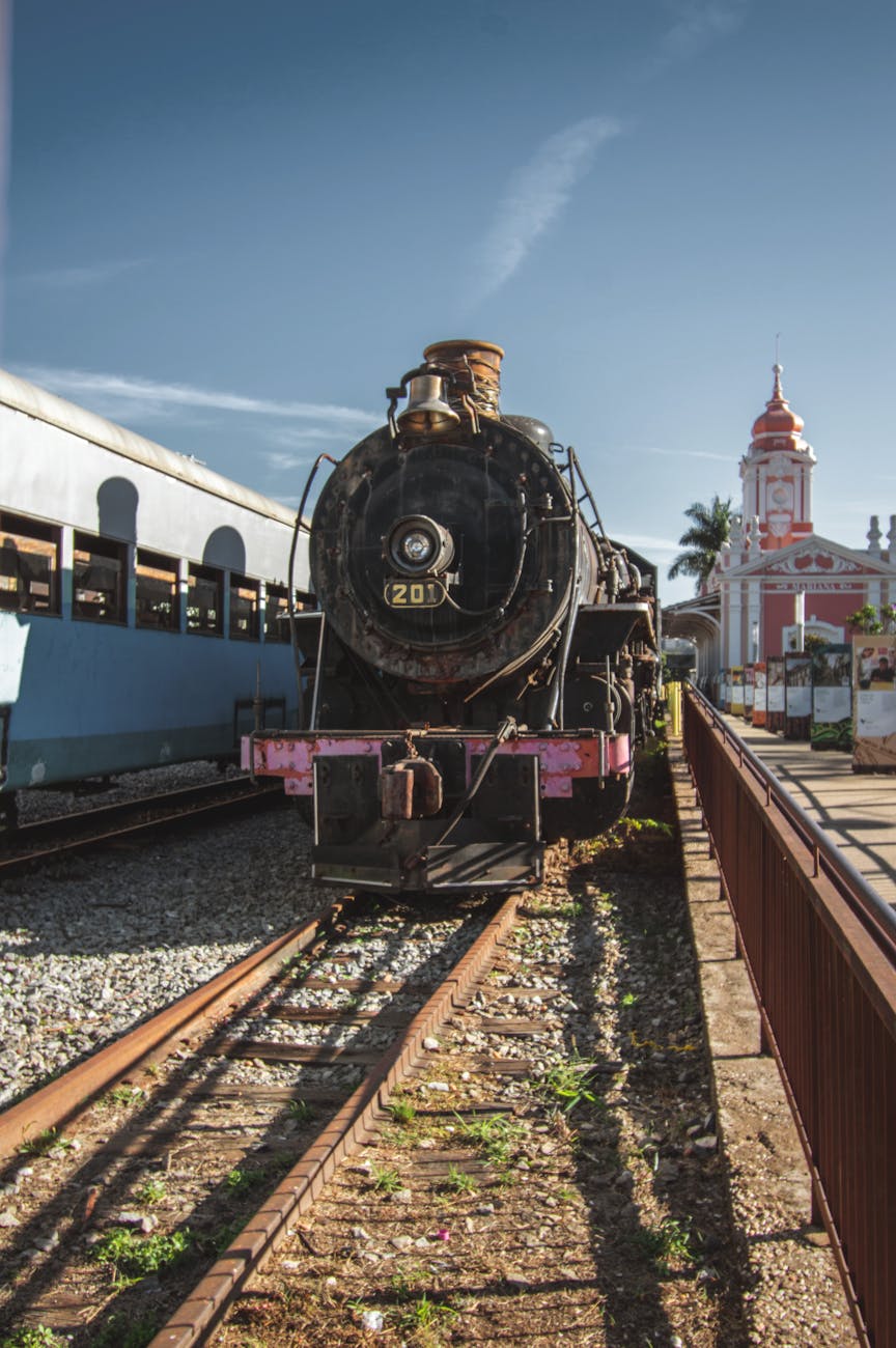 Historic steam train and station under a clear blue sky.